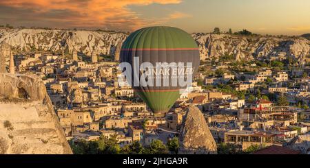GOREME/TURKEY - June 27, 2022: hot air balloon flies low over the city of goreme Stock Photo