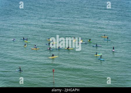 Tenby, Wales - May 2021 : Swimmers Paddle boarding on a hot day in Tenby coast , Carmarthen Bay, Pembrokeshire Stock Photo