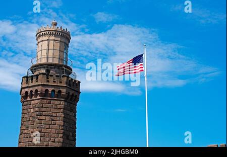 United States flag waving in the breeze next to the north tower of the historic Navesink Twin Lighthouses in Highlands, New Jersey, USA -10 Stock Photo