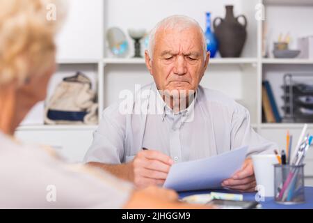 Upset senior man discussing with wife bills Stock Photo