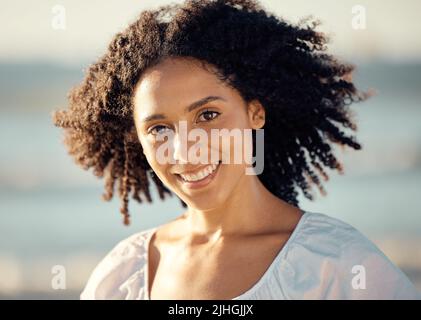 Portrait of a happy young mixed trace woman face with a curly afro, beautiful hispanic woman enjoying some time at the beach. Closeup shot of a Stock Photo