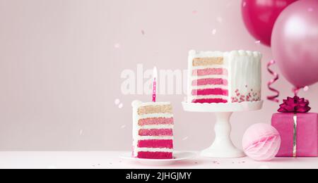 Pink ombre birthday cake with balloons and slice of birthday cake and candle Stock Photo