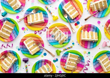 Colorful birthday party background of birthday cake slices on colorful rainbow plates at a birthday party Stock Photo