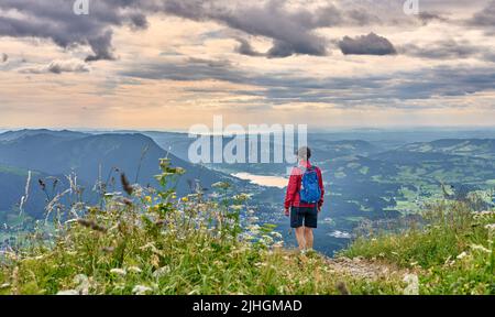 nice senior woman hiking at Mount Gruenten in the Allgaeu Alps with awesomw view over Iller valley to Lake Alpsee and Lake of Constanz, Bodensee,  Bav Stock Photo