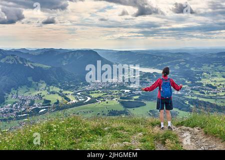 nice senior woman hiking at Mount Gruenten in the Allgaeu Alps with awesomw view over Iller valley to Lake Alpsee and Lake of Constanz, Bodensee,  Bav Stock Photo