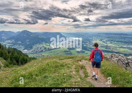 nice senior woman hiking at Mount Gruenten in the Allgaeu Alps with awesomw view over Iller valley to Lake Alpsee and Lake of Constanz, Bodensee,  Bav Stock Photo