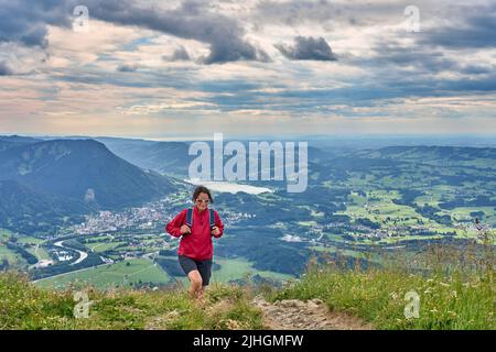 nice senior woman hiking at Mount Gruenten in the Allgaeu Alps with awesomw view over Iller valley to Lake Alpsee and Lake of Constanz, Bodensee,  Bav Stock Photo