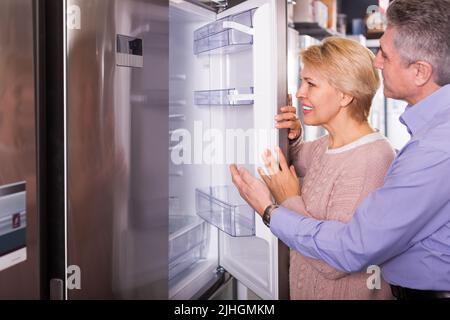 Mature couple chooses refrigerator in shop Stock Photo