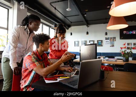 Multiracial business colleagues discussing over laptop in meeting at creative office Stock Photo