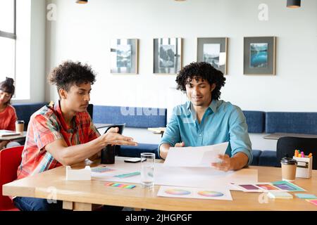 Creative biracial businessmen discussing over charts at table in office Stock Photo