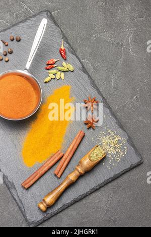 Dry spices in wooden scoop. Ground turmeric in metal bowl and paprika on table. Cinnamon sticks, star anise and cardamom. Copy space. Flat lay. Black Stock Photo