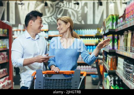 Happy shoppers Asian man and woman buy and choose goods in supermarket, family shopping Stock Photo
