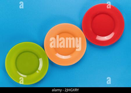 Empty bright colored plates row on blue background top view with copy space Stock Photo