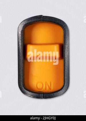Bright orange switch with an inscription "On" on it. Clipping path on the swith. On white plastic background Stock Photo