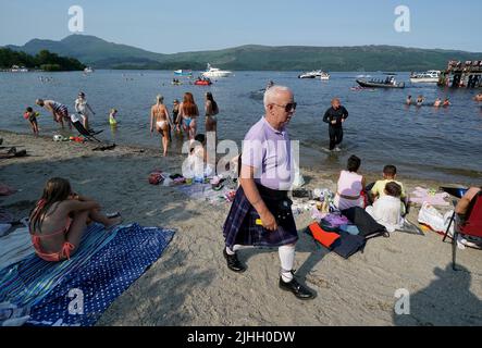 People on the beach in the village of Luss on Loch Lomond, in Argyll and Bute, Scotland. Picture date: Monday July 18, 2022. Stock Photo