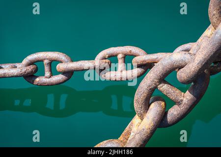 Detail of large ship's anchor chain midway between the vessel's bow and its ocean mooring. Stock Photo