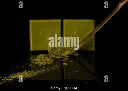Japanese green chocolate with wooden matcha tea spoon. Isolated on black Background Stock Photo
