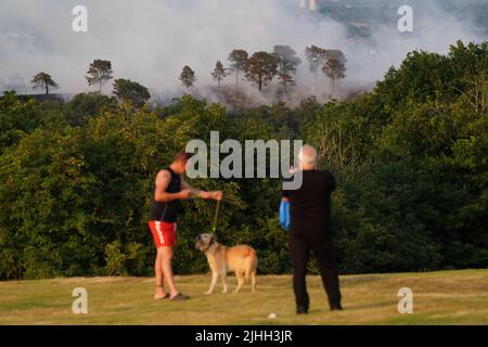 People watch a large wildfire that has broken out in woodland at Lickey Hills Country Park on the edge of Birmingham. About sixty firefighters are tackling the blaze which broke out at the beauty spot earlier today. Picture date: Monday July 18, 2022. Stock Photo