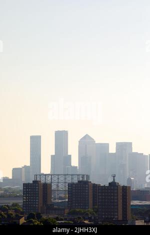 London, UK-5.7.22: silhouette of the Canary Wharf central business district in a midday haze as seen from Southwark. Located on the Isle of Dogs It is Stock Photo