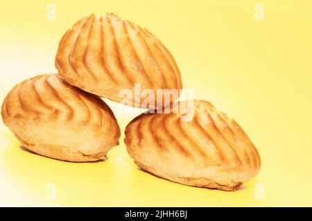 Three delicious appetizing profiterole eclair cakes on yellow background Stock Photo