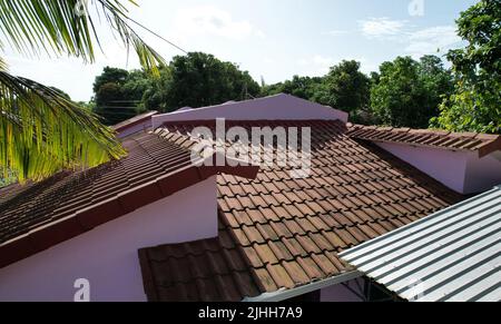 Red clay tiles and metal roof in residential house on blue sky background Stock Photo