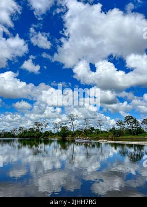 Skiff boats of ecotourists on the Pacaya river in Loreto Peru with beautiful clouds and reflections Stock Photo