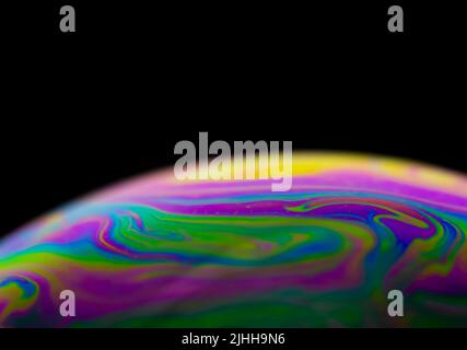 Colorful stripes on soap bubble with black background and selective focus. Stock Photo