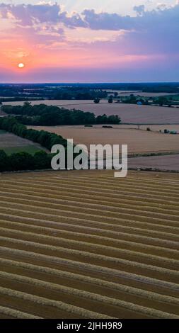 Aerial portrait Sunset in Suffolk with freshly harvested wheat field in the foreground Stock Photo