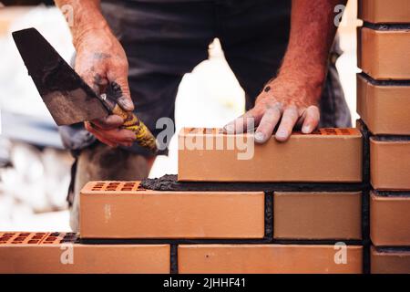 Builder laying bricks on construction site Stock Photo