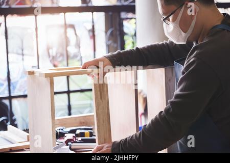 A carpenter measures the planks to assemble the parts, and build a wooden table for the customer Stock Photo