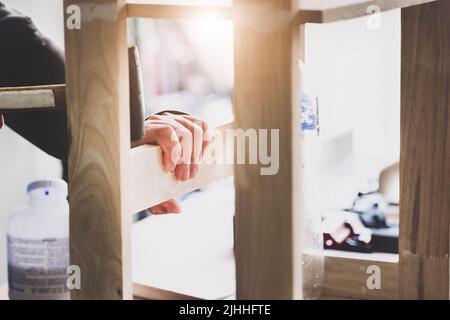 A carpenter measures the planks to assemble the parts and build a wooden table for the customer Stock Photo