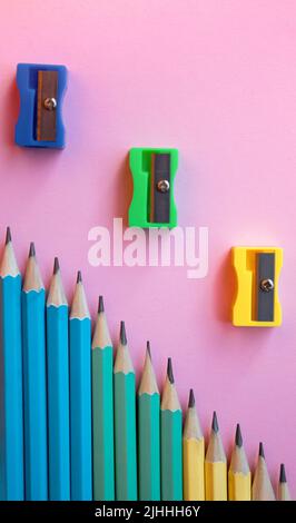 Colored wooden pencils and pencil sharpener on pink background. Top view, flat lay. Back to school, education concept. Stock Photo