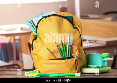 School backpack and stationery on table in classroom Stock Photo