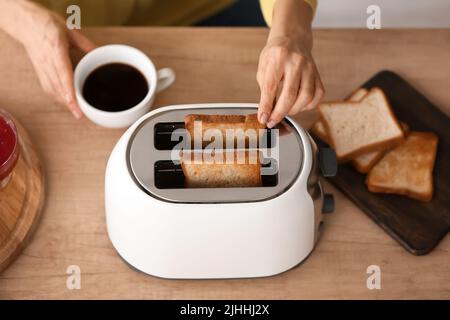 Mature woman making tasty toasts and drinking coffee in kitchen, top view Stock Photo