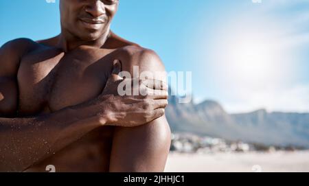 Closeup shot of an african american muscular athletic man holding his shoulder in pain. Black unrecognizable male suffering from arthritis in his arm Stock Photo