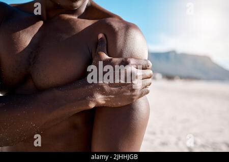 Closeup shot of an african american muscular athletic man holding his shoulder in pain. Black unrecognizable male suffering from arthritis in his arm Stock Photo