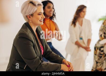 Group of diverse businesswomen smiling happily during a conference meeting in a modern workplace. Successful businesswomen working together in an all- Stock Photo