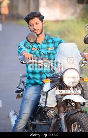 An Indian man sitting on a motorbike and posing for photo Stock Photo