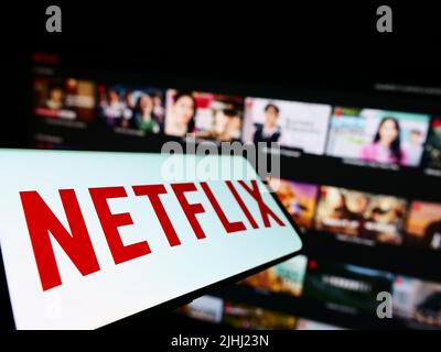 Smartphone with logo of American video streaming company Netflix Inc. on screen in front of business website. Focus on left of phone display. Stock Photo