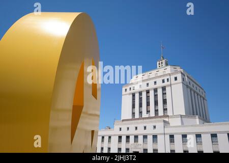 A view of the County Courthouse with a yellow metal peace sign sculpture by the artist, Tony Labat. At the Oakland Museum of Art in Oakland, Californi Stock Photo