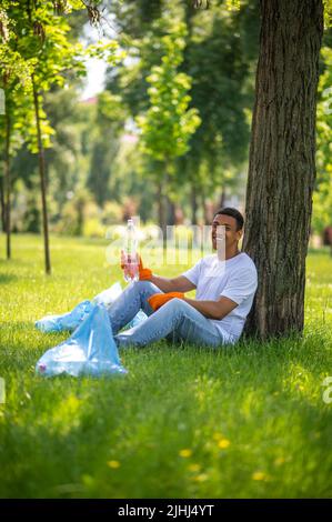 Guy sitting under tree smiling at camera Stock Photo