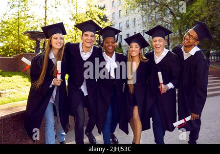 Portrait of joyful group of multiracial students celebrating graduation day together. Stock Photo