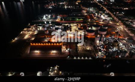 A high, aerial view looking at manufacturing facilities and industrial storage tanks while illuminated late at night. Stock Photo