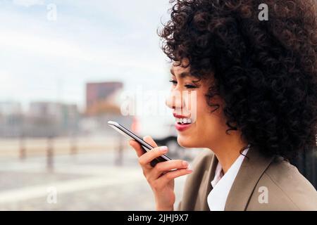 woman smiles recording a message with a mobile Stock Photo
