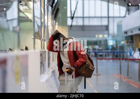 Frustrated sad young African man passenger having problems with check-in for flight Stock Photo