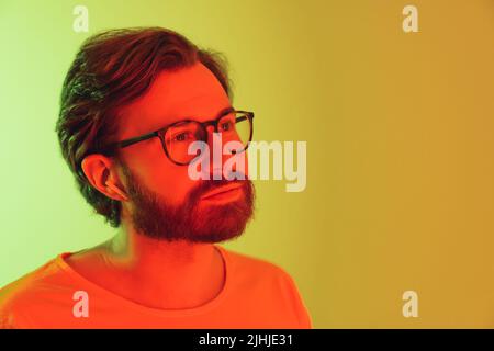 Portrait of an young hipster looking off the camera and thinking. Neon Lights. High quality photo Stock Photo