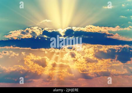 Colorful dramatic summer sunset with rays of sun from clouds. Beautiful sunshine in heaven. Stock Photo