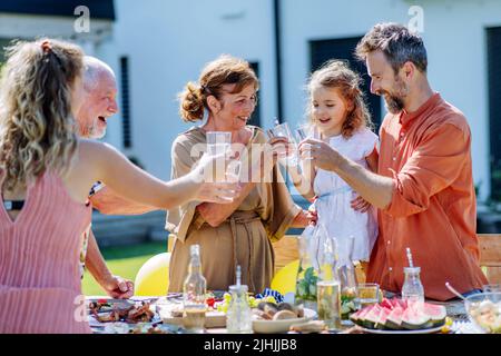 Multi generation family having garden party celebration, toasting and laughing. Stock Photo