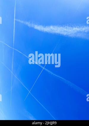 Many contrails cross each other in the blue sky Stock Photo