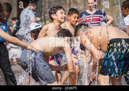 London, UK - 18 July, 2022 - Heatwave in London, children playing with water to cool at the fountains at Granary Square in Kings Cross Stock Photo